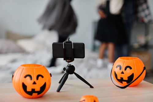 Background image of smartphone on tripod with Halloween buckets and ornaments, Halloween live stream concept, copy space