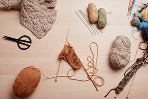 Top view flat lay of wool and knitting supplies on wooden table, copy space