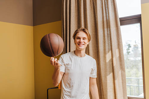 selective focus of happy man looking at basketball at home, end of quarantine concept
