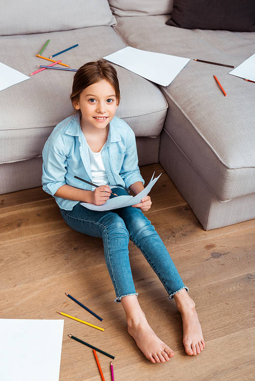 overhead view of happy child sitting on floor and drawing in living room