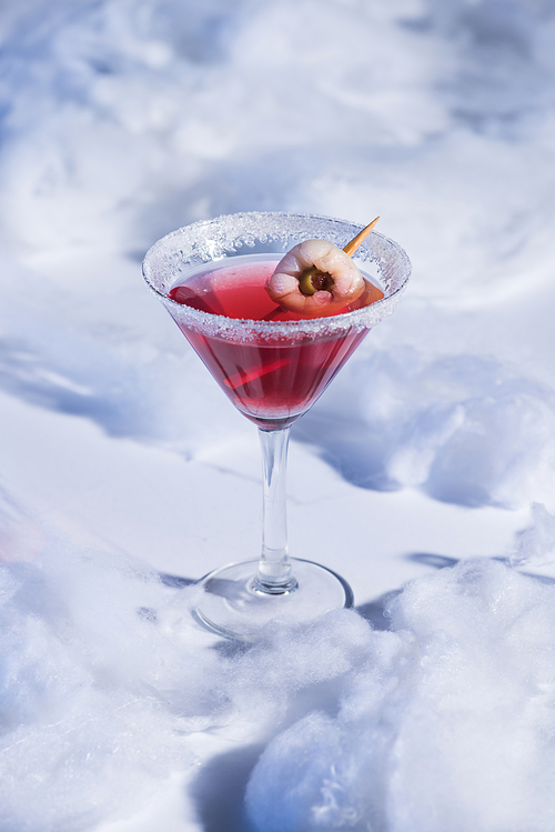 red Halloween cocktail in glass on white surface with cotton wool