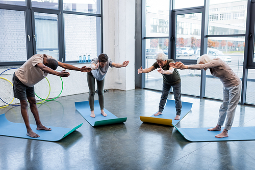 Barefoot multiethnic people practicing yoga on mats in sports center